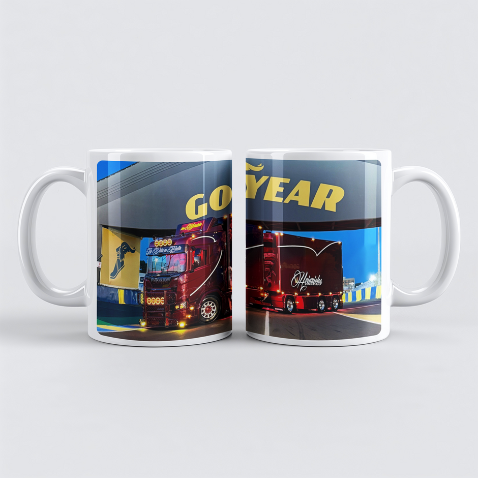 Weiße Tasse “24h Le Mans” mit Foto des roten Heinrichs Hängerzugs auf der Rennstrecke bei Abenddämmerung